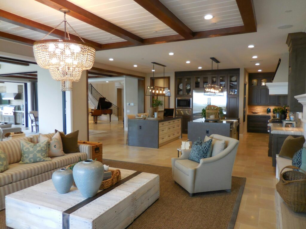 Luxury Home Sales Spacious living room with elegant decor and an open kitchen area, featuring a chandelier and comfortable furnishings.