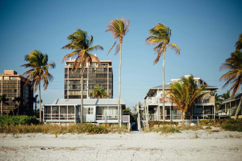 STVR Selling Sunny beachfront view with palm trees and modern houses, perfect for a tropical getaway.
