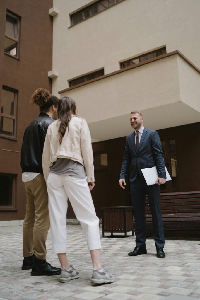 Top-Rated Realtors in Yorba Linda, CA (2026 Guide) A professional realtor showing a new apartment to a young couple in a city setting.